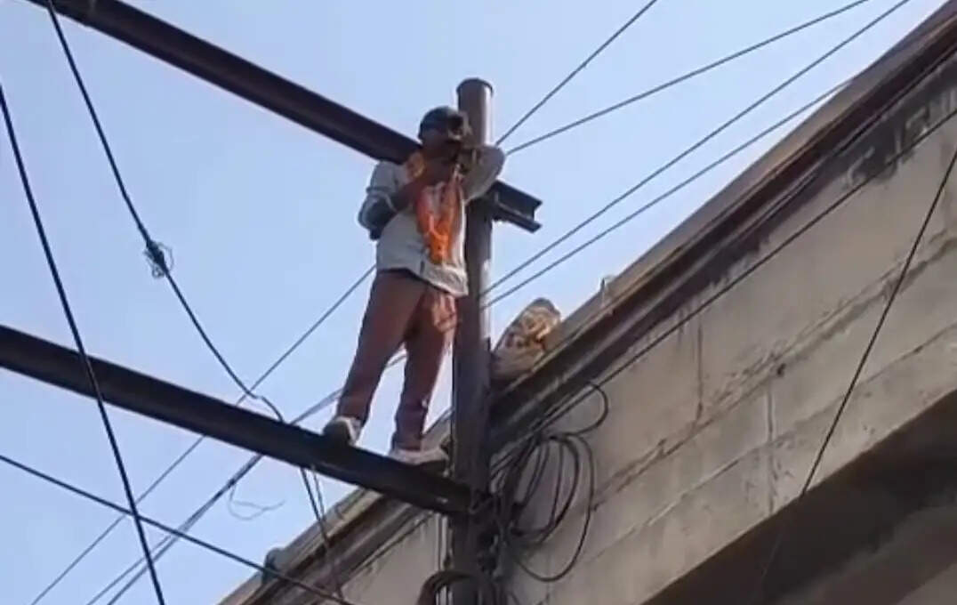 आंखों पर चश्मा, गले में माला, विद्युत पोल पर चढ़ा युवक